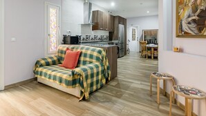 A modern apartment with a kitchenette, a dining area, and a living space with a sofa. - Madrid Centro - 3 bedroom and 2 bathroom apartment with 2 terraces (Ciudad de Madrid)