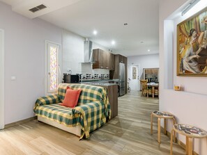 A modern apartment with a kitchenette, a dining area, and a living space with a sofa. - Madrid Centro - 3 bedroom and 2 bathroom apartment with 2 terraces (Ciudad de Madrid)