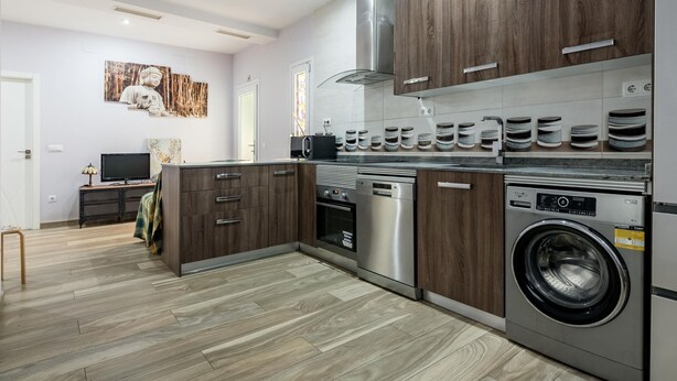 A modern kitchen with wooden cabinets, stainless steel appliances, and a built-in washing machine. - Madrid Centro - 3 bedroom and 2 bathroom apartment with 2 terraces (Ciudad de Madrid)