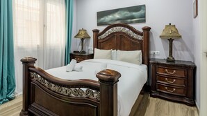 A bedroom with a wooden bed, two bedside tables with lamps, a large window with sheer curtains, and a painting on the wall. - Madrid Centro - 3 bedroom and 2 bathroom apartment with 2 terraces (Ciudad de Madrid)