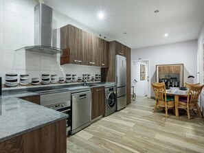 A modern kitchen with a built-in oven, washing machine, and refrigerator. - Madrid Centro - 3 bedroom and 2 bathroom apartment with 2 terraces (Ciudad de Madrid)