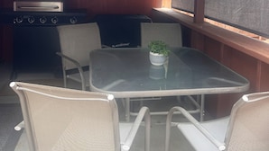 Un espacio de descanso al aire libre con techo, una parrilla, sillas y una mesa.