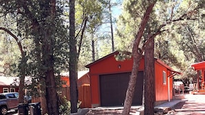 Un edificio rojo con un garaje, rodeado de árboles y senderos de grava.