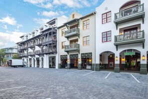 Un hotel con varios pisos, balcones y un área de entrada pavimentada.