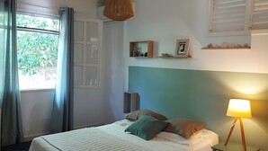 Ein Schlafzimmer mit einem Bett, einer Nachttischlampe, einer Pendelleuchte, einem Fenster mit Vorhängen und einem Regal mit dekorativen Gegenständen.