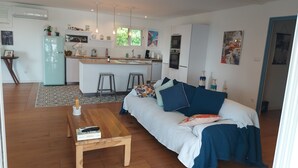 Ein modernes Wohnzimmer mit einer Couch, einem Couchtisch und einer Küchenzeile im Hintergrund.