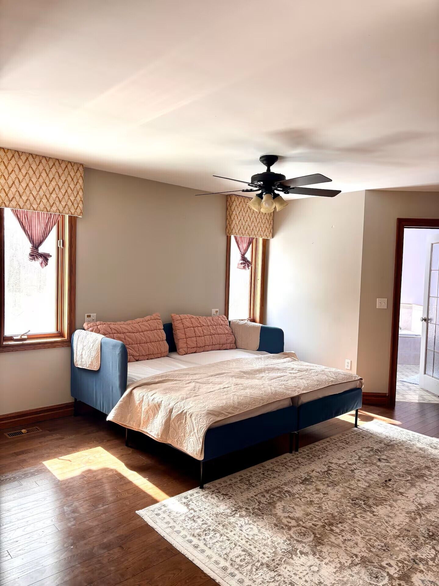 A bedroom with a bed, a ceiling fan, and a window with curtains.