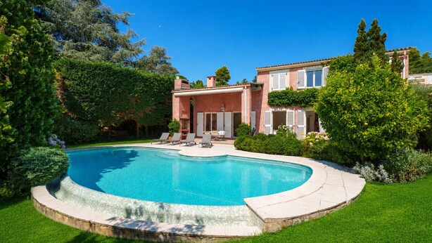A swimming pool with a curved edge, surrounded by a well-maintained lawn and various trees. - Villa Harmonie - Welkeys (Villeneuve-Loubet)