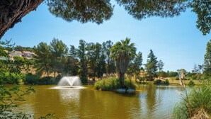 A pond with a fountain, surrounded by trees and greenery. - Villa Harmonie - Welkeys (Villeneuve-Loubet)