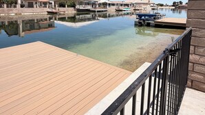 Una propiedad frente al agua con un muelle de madera, una vista despejada del agua y una hilera de edificios con balcones.