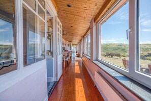 Ein Korridor mit Holzboden, großen Fenstern und Blick ins Freie.