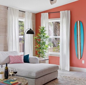 A cozy living room with a grey sofa, a small side table with a book and glasses, and a plant. - Flamingo Point | Steps from the Beach (St Augustne)