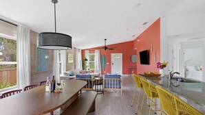 Une cuisine spacieuse avec une longue table en bois, des tabourets de bar jaunes et un grand îlot central doté d’un évier.