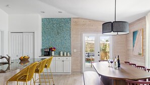 Une cuisine moderne avec un îlot central, des meubles blancs et un pare-feu bleu.