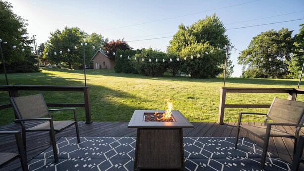 A deck with a square fire pit, two chairs, and a patterned rug. - White Juniper Spacious 4-BR Retreat in Ohio's Mini Switzerland (Sugarcreek)