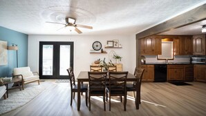 A dining area with a table and chairs, a ceiling fan, and wooden cabinets in the adjacent kitchen. - White Juniper Spacious 4-BR Retreat in Ohio's Mini Switzerland (Sugarcreek)