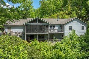 Une maison à deux étages avec un balcon, une cour clôturée et une végétation luxuriante tout autour.