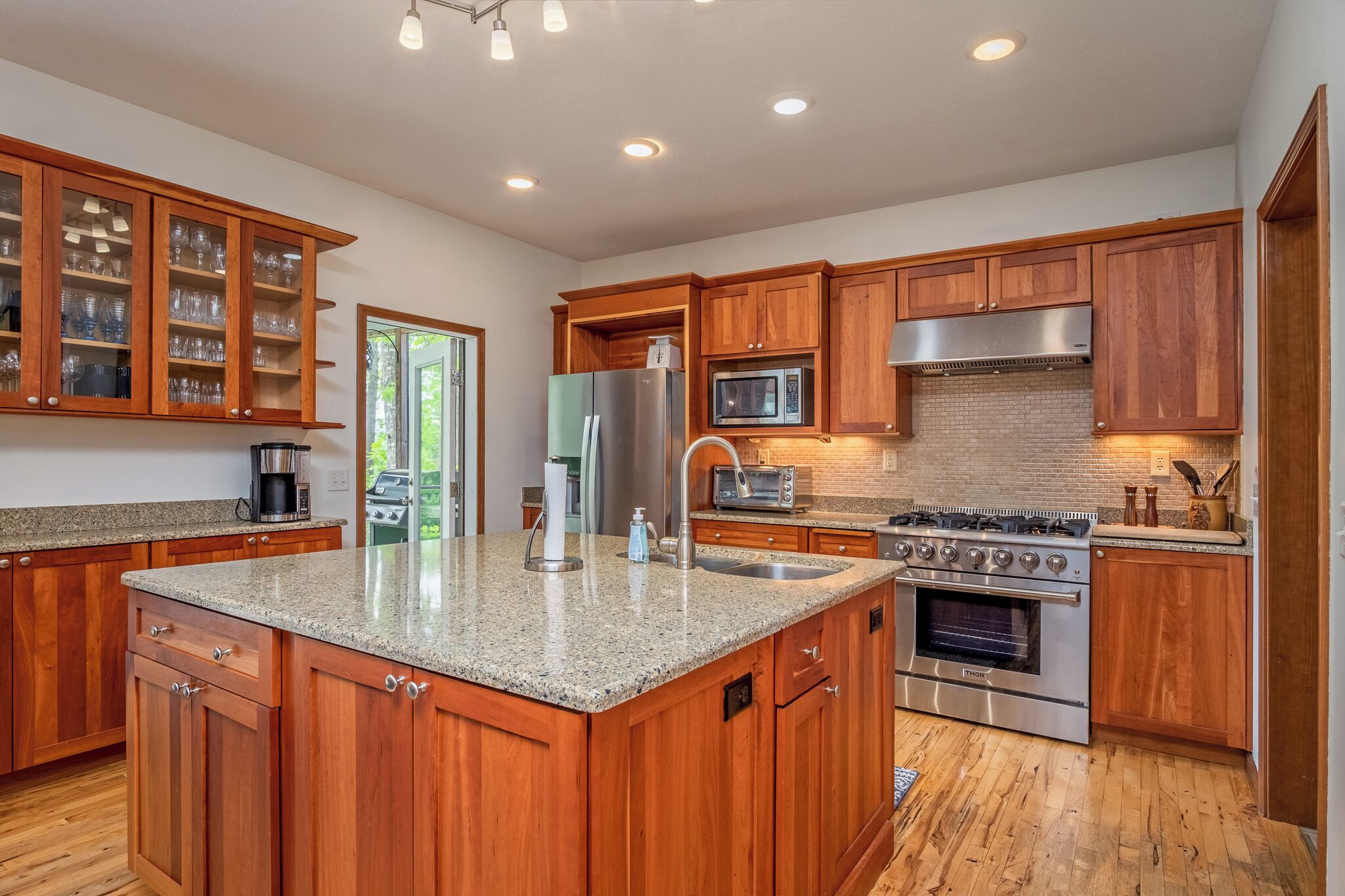 A kitchen with wooden cabinets, granite countertops, stainless steel appliances, and a large island.