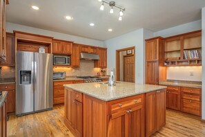 A kitchen with wooden cabinets, stainless steel appliances, granite countertops, and recessed lighting.