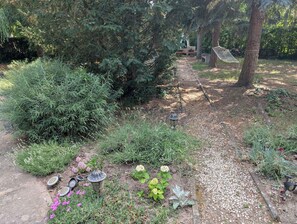 A garden with a gravel path, various shrubs, and a hammock. - Holiday flat on the upper floor with Wi-Fi and air conditioning (Zamárdi)
