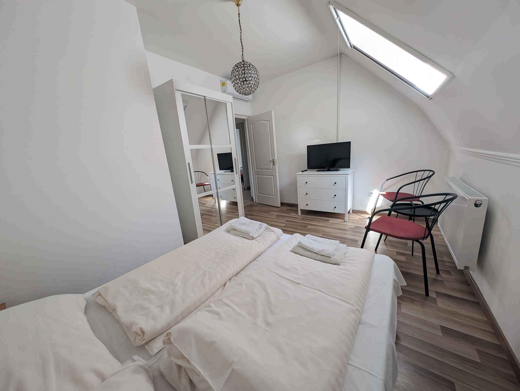 Un dormitorio con cama, televisión, silla y escritorio.