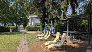 Un jardí amb seients de relaxació, una taula i una pèrgola.