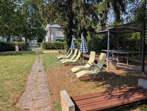 A garden with lounge chairs, a table, and a pergola. - Holiday flat on the upper floor with Wi-Fi and air conditioning (Zamárdi)
