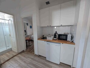 A compact kitchen with white cabinets, a microwave, a dishwasher, and a wooden countertop. - Holiday flat on the upper floor with Wi-Fi and air conditioning (Zamárdi)