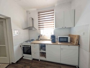 A compact kitchen with white cabinets, a gas stove, a microwave, and a built-in oven. - Holiday flat on the upper floor with Wi-Fi and air conditioning (Zamárdi)