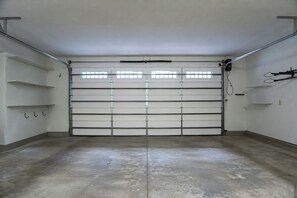 Eine Garage mit geschlossenem Garagentor, einem Betonboden und Metallregalen an den Wänden.