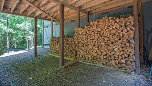 A covered wooden structure with a pile of firewood and a swing set. - 3BR Retreat in Connestee Falls with Fireplace, Community Pool, and Garage (Brevard)