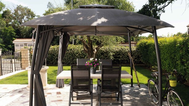 A covered outdoor seating area with a table and chairs, a bicycle, and a potted plant. - Holiday apartment near Pical Beach (Poreč)