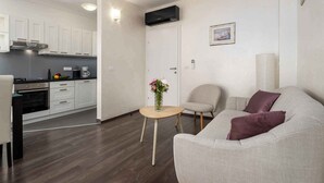 A modern living space with a kitchen, a sofa, a chair, and a small table with a vase. - Holiday apartment near Pical Beach (Poreč)