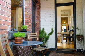 A brick exterior with a glass door leading to an interior space. - Charming Fitzroy Terrace | Walk, Dine & Explore (Fitzroy)