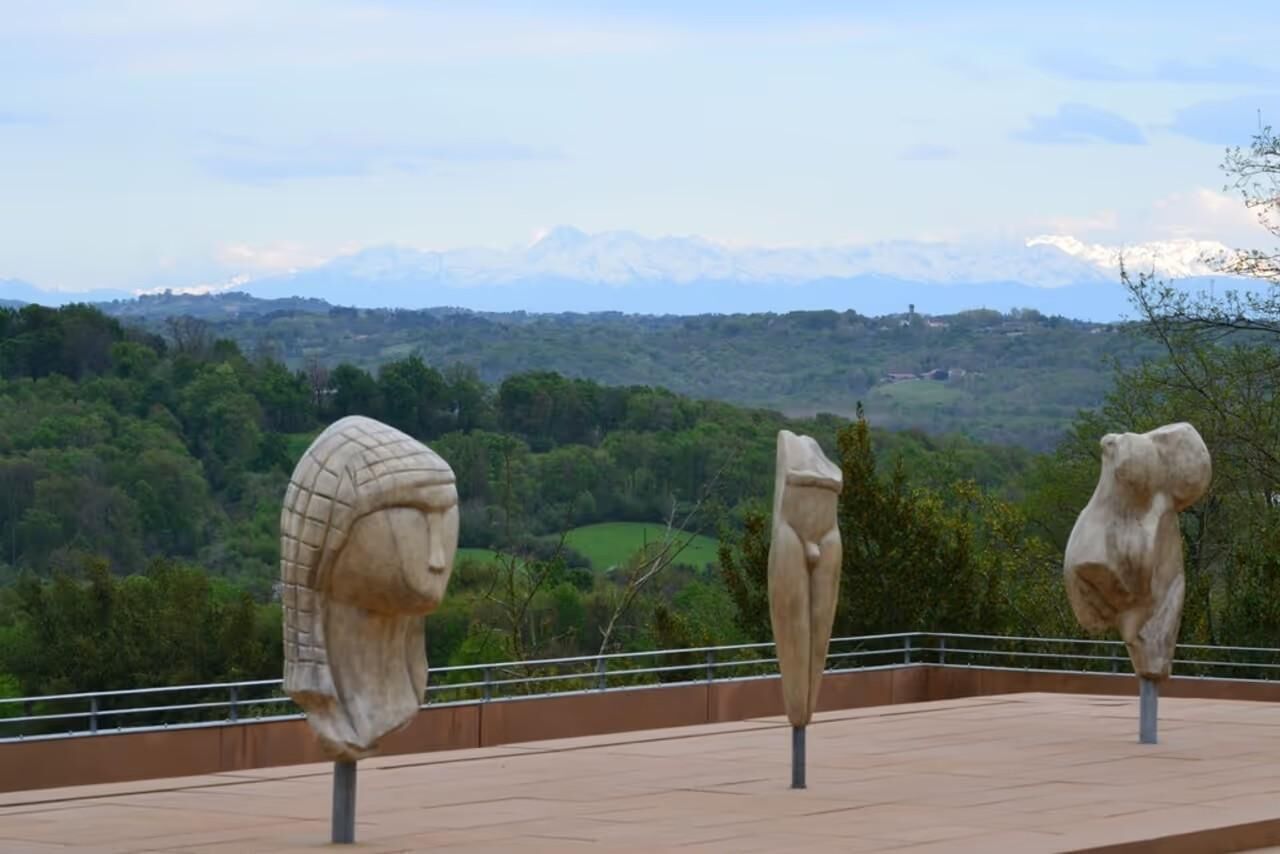 Three stone sculptures on a terrace with a mountainous landscape in the background.