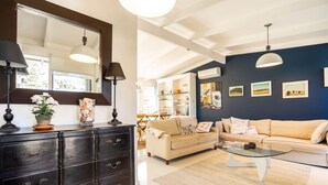 A modern living room with a dark wooden dresser, two cream-colored sofas, a glass coffee table, and a large mirror. - Chiara`s Art Cottage 3BR Coastal Garden Retreat (Sorrento)
