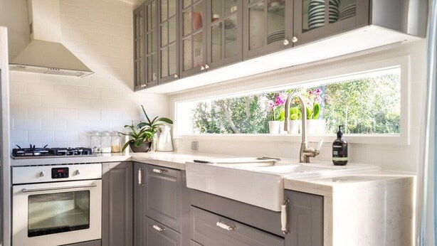 A modern kitchen with grey cabinets, a built-in oven, a gas stove, and a window with a view of greenery. - Chiara`s Art Cottage 3BR Coastal Garden Retreat (Sorrento)