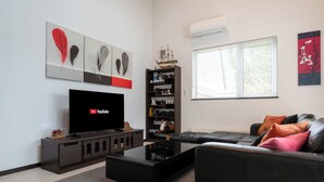 Una sala de estar moderna con una televisión de pantalla plana, una estantería, un sofá y una mesa de centro.