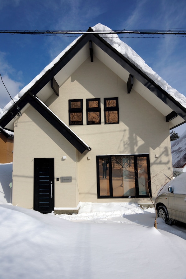 A two-story house with a snow-covered roof and a black door. - MOMIJI GEORGIA (Furano-shi /Kitanomine-cho)