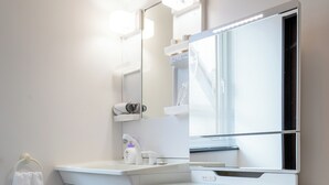 Un baño moderno con tocador blanco, espejo y perchero.