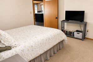 Un dormitorio con una cama, un televisor sobre un mueble bajo y una estantería.