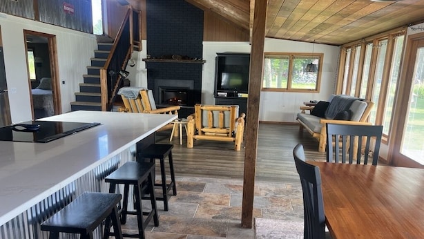 A modern kitchen with a large island, wooden chairs, and a fireplace.