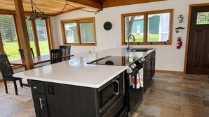 A kitchen with a central island, a sink, and a stove. There are windows and a door visible.