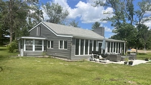 A single-story house with a covered porch, a barbecue area, and a well-maintained lawn.
