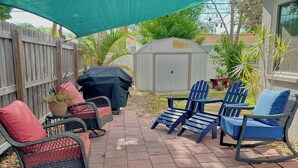 Eine Terrasse mit Gartenmöbeln, einem Grill und einem überdachten Bereich.