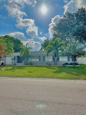A residential area with a house, a lawn, and a street. - Charming Mid Century Modern Home w/office and large outdoor space (St. Petersburg)