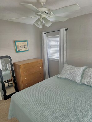 A bedroom with a bed, dresser, ceiling fan, window with blinds, and a framed picture on the wall. - Charming Mid Century Modern Home w/office and large outdoor space (St. Petersburg)