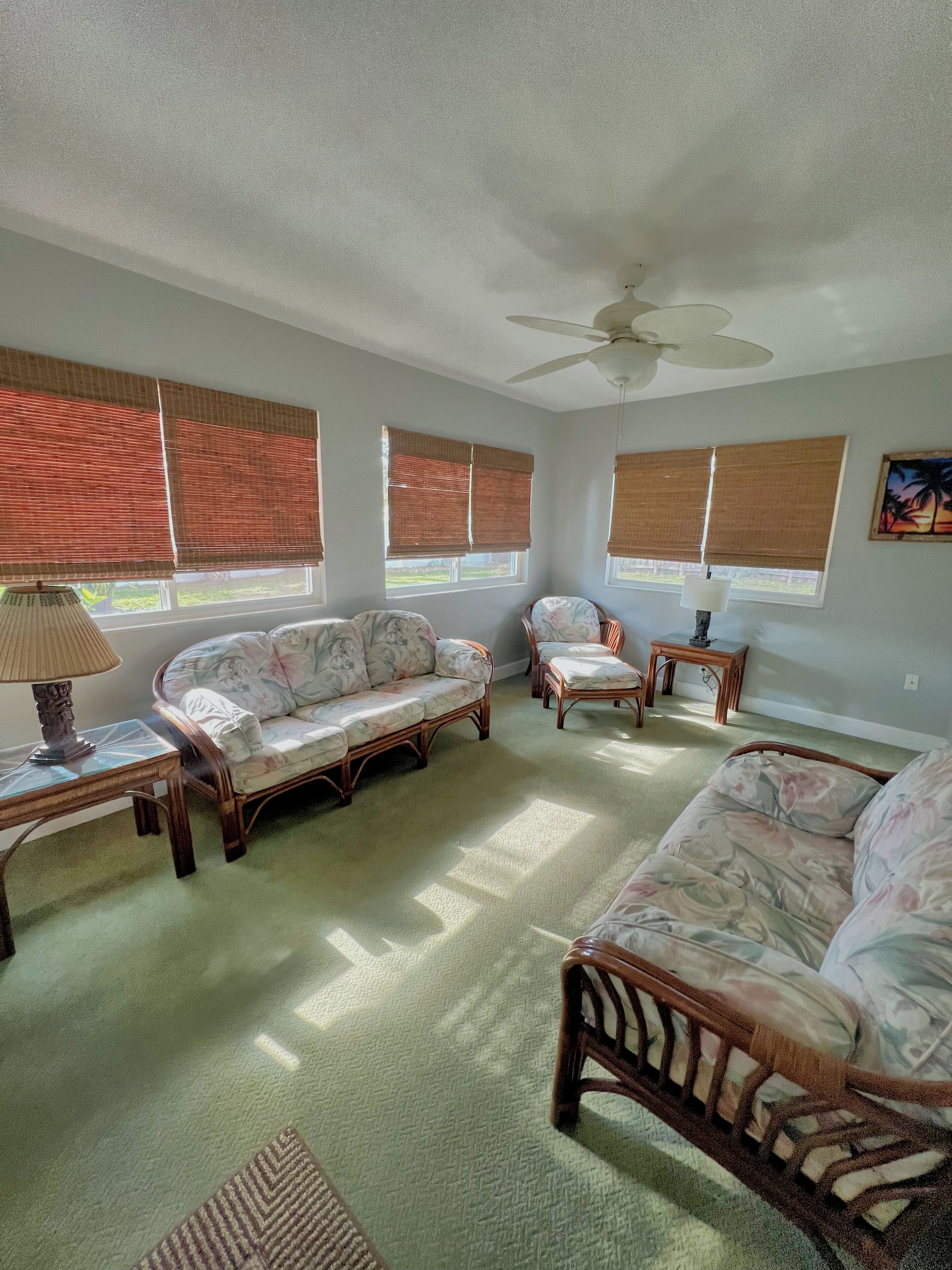 A living room with a sofa, chairs, a coffee table, a lamp, and a ceiling fan.
