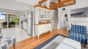 Eine geräumige Küche mit weißen Schränken, einem Edelstahlkühlschrank und einer Holztreppe.