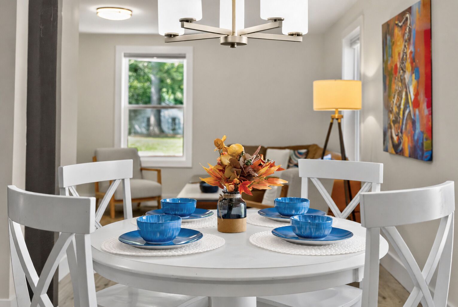 A dining area with a white table, blue bowls, and a vase with flowers.